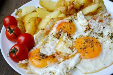 Büyük tabak kızarmış yumurta, patates kızartması ve domates - geleneksel bir kahvaltı dolu yuvarlak