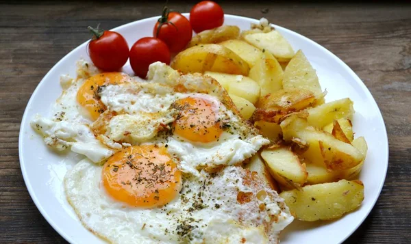 Grote ronde plaat vol met gebakken eieren, patat en cherry tomaten - een traditionele continentaal ontbijt — Stockfoto