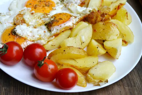 Grote ronde plaat vol met gebakken eieren, patat en cherry tomaten - een traditionele continentaal ontbijt — Stockfoto