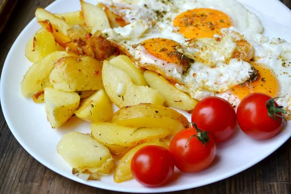 Grote ronde plaat vol met gebakken eieren, patat en cherry tomaten - een traditionele continentaal ontbijt — Stockfoto