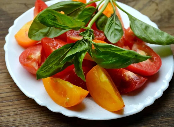 Yellow and red tomatoes on a plate with fresh basil — Stock Photo, Image