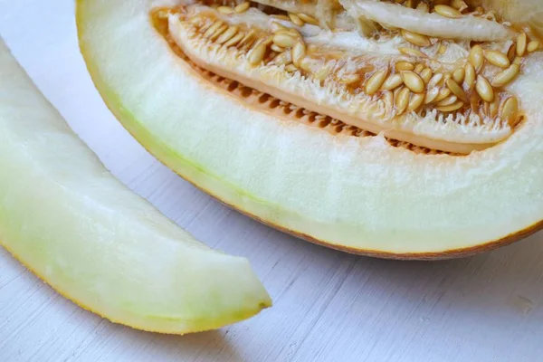 Gustoso melone arancione tagliato a metà su tavoletta di legno bianca — Foto Stock