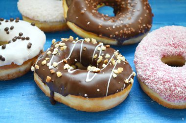 Mavi ahşap tahta üzerinde lezzetli donuts topluluğu