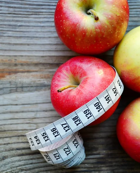 Concepto de dieta con manzanas rojas y amarillas y cinta métrica blanca en mesa de madera —  Fotos de Stock