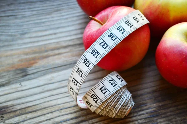 Conceito de dieta com maçãs vermelhas e amarelas e fita métrica branca na mesa de madeira — Fotografia de Stock