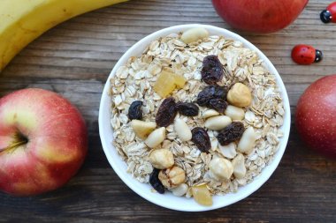 Çiğ yulaf gevreği ile fındık ve ahşap masa üzerinde beyaz kase kuru üzüm