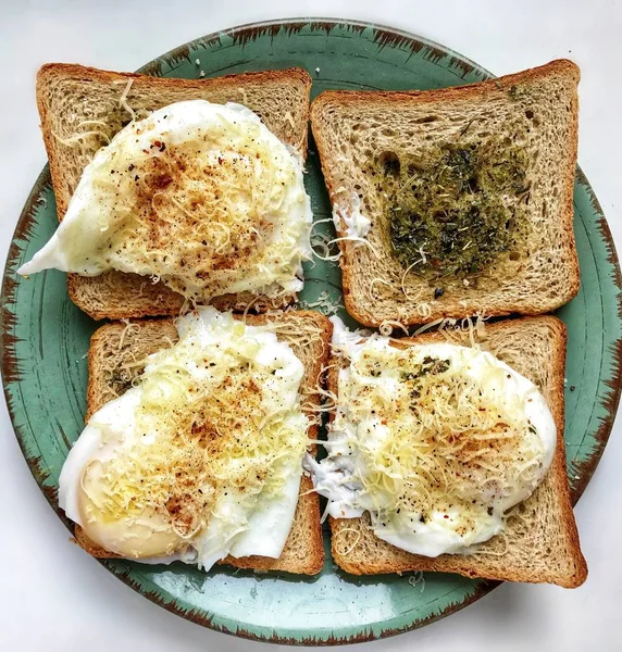 Tasty English breakfast made of toast with herbs and poached Benedict eggs with Parmesan cheese and pepper