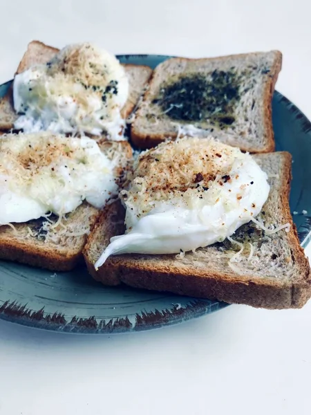 Tasty English breakfast made of toast with herbs and poached Benedict eggs with Parmesan cheese and pepper