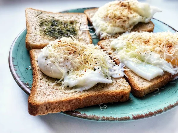 Tasty English breakfast made of toast with herbs and poached Benedict eggs with Parmesan cheese and pepper