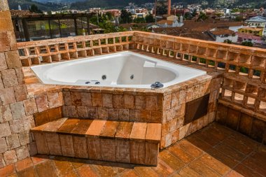 White Jacuzzi located on the corner of a red brick terrace, overlooking the city