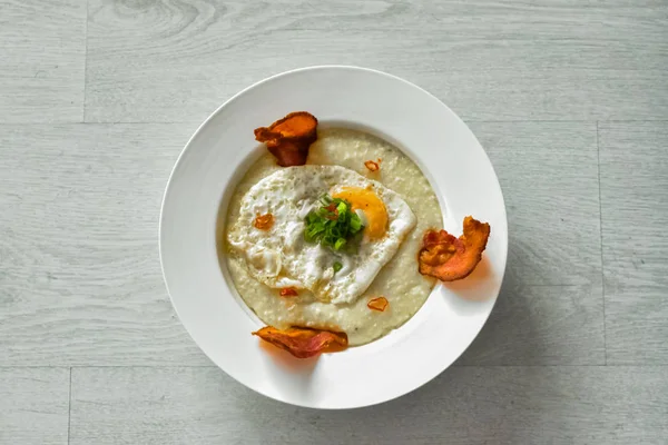 Körner Mit Spiegelei Speck Und Schnittlauch Serviert Auf Einem Weißen lizenzfreie Stockbilder