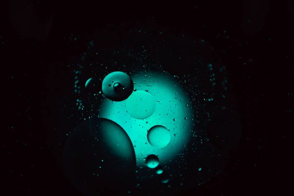 oil droplets from a mixture of water and olive oil illuminated with colored bulb