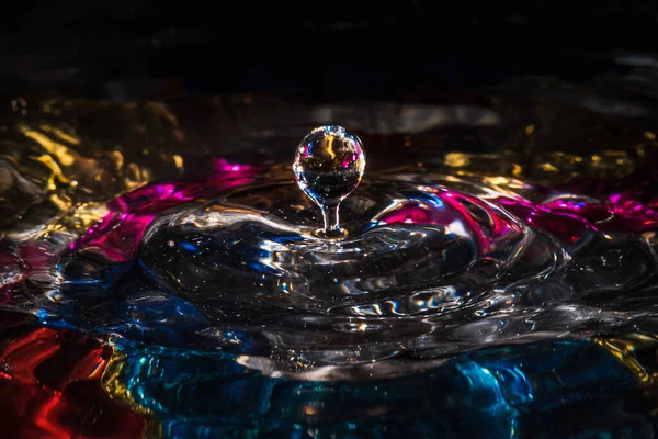 Σταγόνες νερού πιτσιλίζουν σχηματίζοντας κυματισμούς και κύματα και αφηρημένες κολώνες νερού σε ένα πολύχρωμο φόντο — Φωτογραφία Αρχείου
