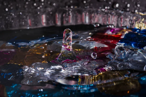 Water drops splash forming ripples and waves and abstract water columns in a colorful background — ストック写真