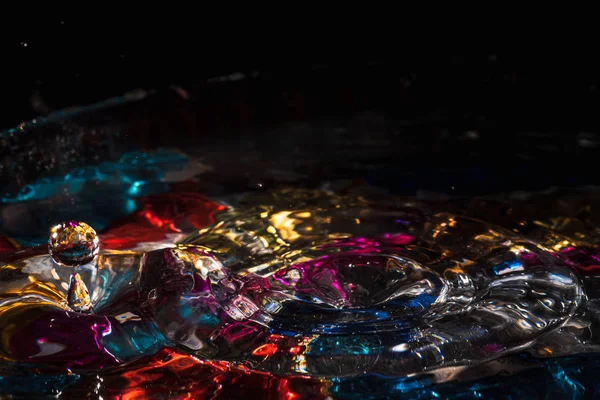 Vatten droppar stänk bildar ringar och vågor och abstrakta vatten kolumner i en färgstark bakgrund — Stockfoto