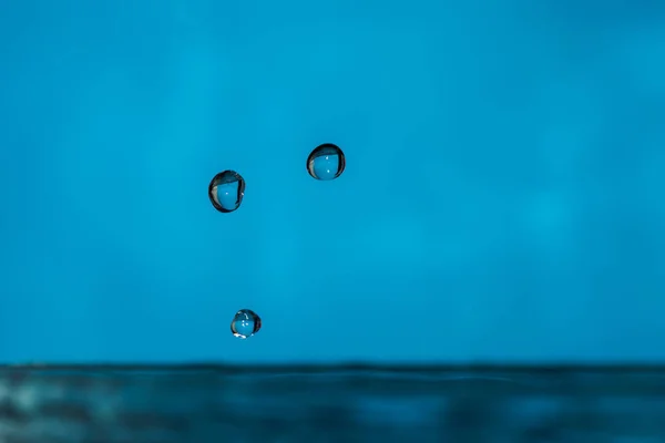 Water drops splash forming ripples and waves and abstract water columns — Stock Photo, Image