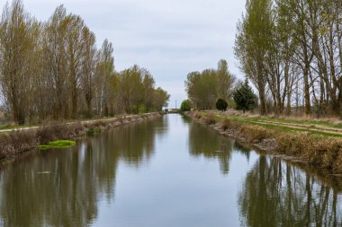 sailing through tha canal de castilla, castile channel, on a cold and cloudy spring morning, palencia, spain