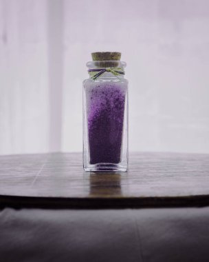 Beyaz arkaplanlı spa tedavilerini gevşetmek için lavanta banyosu tuzu ile süslü bir şişe.