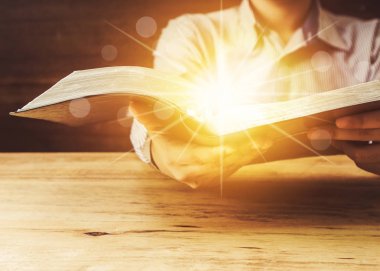 Kutsal İncil 'i elinde yıldızlı ve tahta masaya yansıyan Bokeh ışığıyla tutan bir adama yaklaş. Uzayı kopyala Tanrı 'nın sözlerinin Hıristiyan arka plan gücü kavramı.