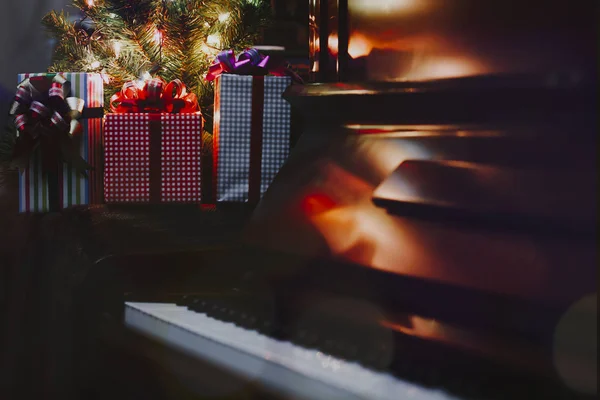 Noel hediyesi kutuları piyano tuşlarında ve Noel ağacı da arka planda, Vintage ton