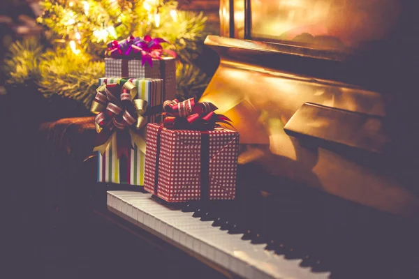 Noel hediyesi kutuları piyano tuşlarında ve Noel ağacı da arka planda, Vintage ton
