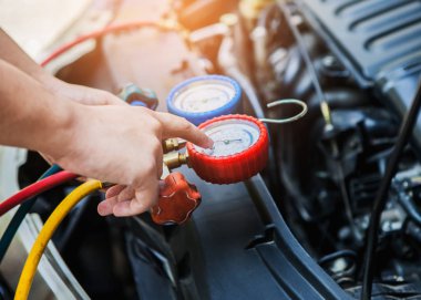 Otomobil tamircisi elleri araba garajındaki klimayı kontrol etmek ve tamir etmek için monitör tutuyor.