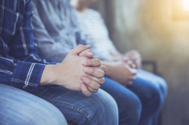 Hıristiyan küçük grup ahşap bir masanın etrafında birlikte dua ediyor. Sınıf, bağlılık ve dua kavramında bulanık bir İncil sayfası var.