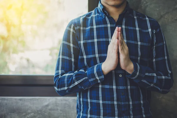 Duvarın üzerinde dua eden bir adam. Pencere ışığı, Hıristiyan sembolü ve arka planıyla.
