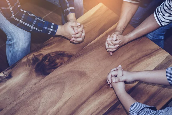 Hıristiyanlar ahşap bir masanın etrafında birlikte dua ederler. Namaz küçük bir grup konseptiyle buluşur.