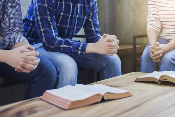 Christian people, a small group are sitting around a wooden table with the holy bible, Christian background for fellowship or pray meeting concept