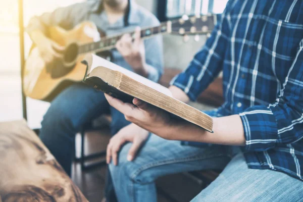 Arkadaşı gitar, övgü ve tapınma konsepti çalarken elinde ilahi kitabı tutan ve şarkı söyleyen bir adama yaklaş.
