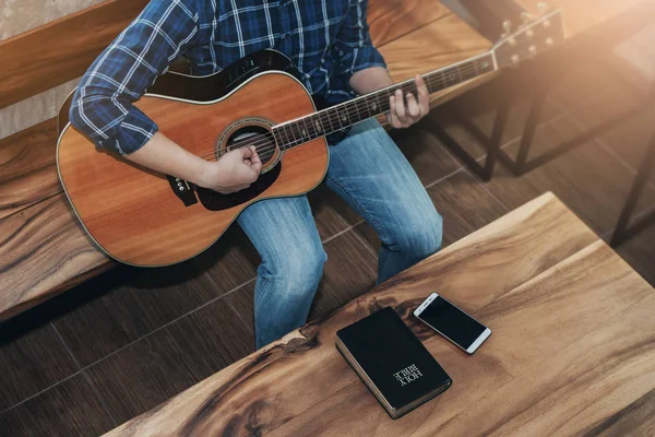 İncille gitar çalan bir adamın ahşap masada telefon çalması, Hıristiyan ibadeti kavramı.