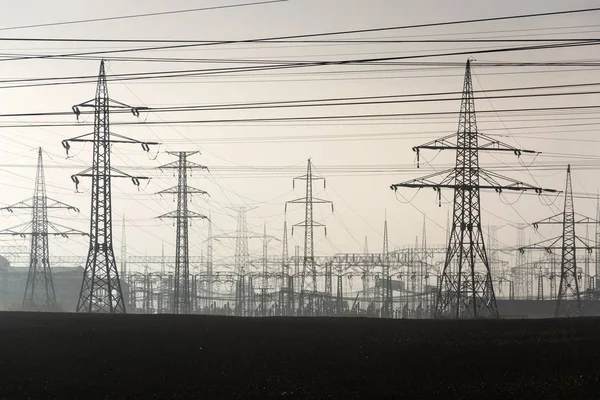 Pilões de electricidade que saem da central eléctrica de distribuição — Fotografia de Stock