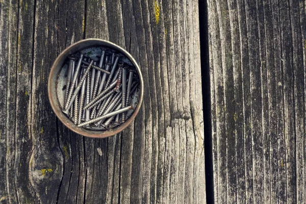 Gefilterde schroeven en bouten in blikje op houten achtergrond — Stockfoto