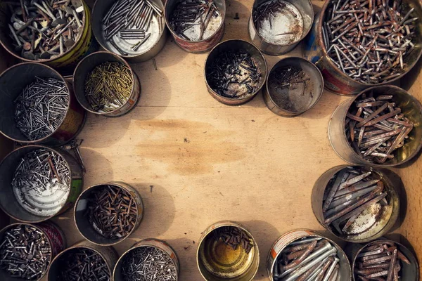 Nails and screws in rusty tin cans on wooden background — Stock Photo, Image