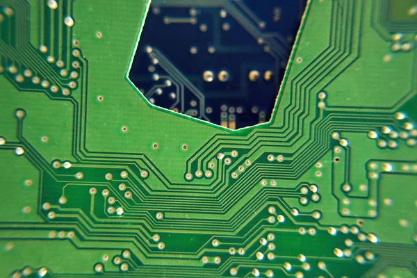 Filtered green computer motherboard circuit above blue motherboard hole — Stock Photo, Image