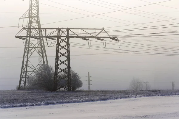 Elektrik direkleri dağıtım güç istasyonu sisli kışın donma — Stok fotoğraf