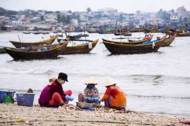 7 Şubat 2012 yılında MUI Ne, Vietnam üzerinde kabukları ile balıkçı tekneleri arka planda işleme kadınlar.