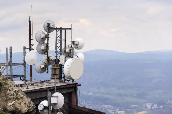 Telecommunication transmitters and aerials with city in background — Stock Photo, Image