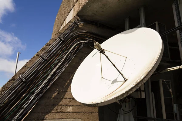 Біла супутникова тарілка з дротами на телекомунікаційній вежі — стокове фото