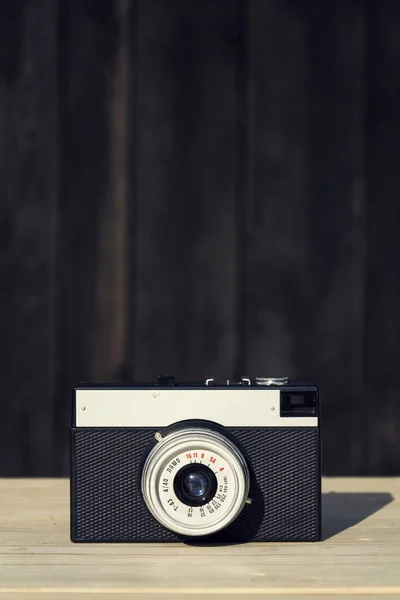 Old vintage filtered camera on wooden background