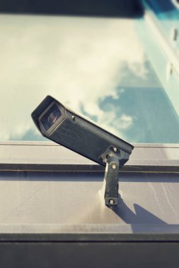 Gri güvenlik kamerası ile mavi gökyüzü bulutlar yansıtan pencere