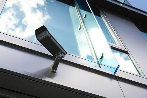 Telecamera di sicurezza grigia con finestra che riflette nuvole di cielo blu — Foto Stock
