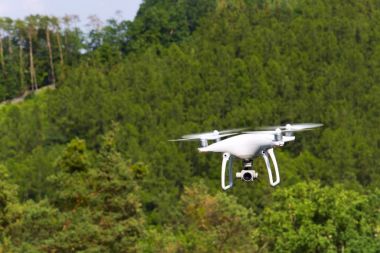 Beyaz dron quadrocopter orman üzerinde uçan kamera ile