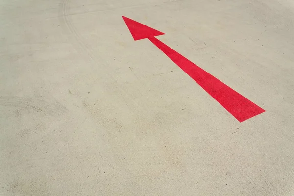 Flèche rouge signe de direction sur la route en béton gris journée ensoleillée — Photo