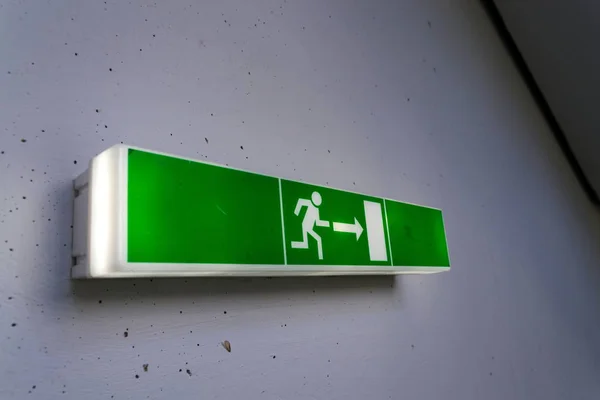 Zöld csillogó menekülés exit jel a fehér beton fal — Stock Fotó
