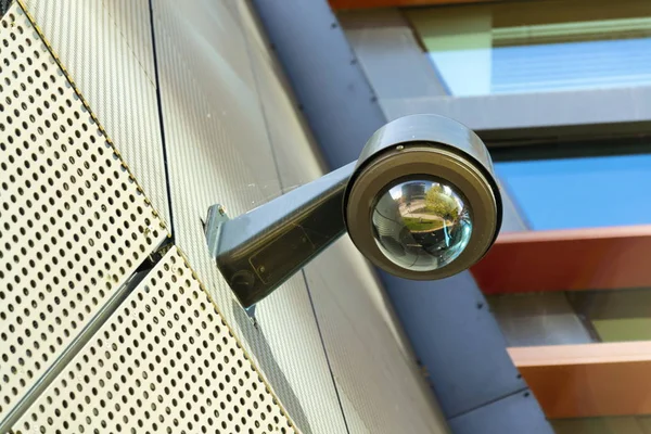 Moderne Überwachungskamera an der Wand mit Fenstern im Hintergrund — Stockfoto