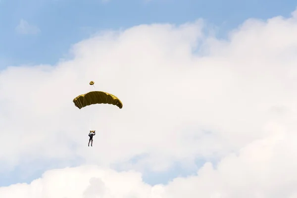 Parachutist skydiving with open yellow parachute clouds blue sky background — Stock Photo, Image