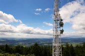 Antény a vysílače na telekomunikační věž s horami v pozadí, modrou oblohou, digitální komunikace a šifrování bezpečnostní koncepce
