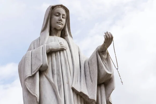 Статуя Девы Марии Четками Руке Голубым Чистым Небом Фоне Стоит — стоковое фото
